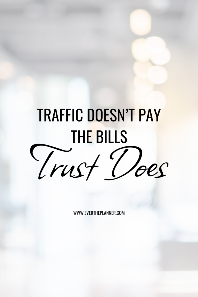 Soft white blurred office background with bold text quote: “Traffic doesn’t pay the bills. Trust does.”